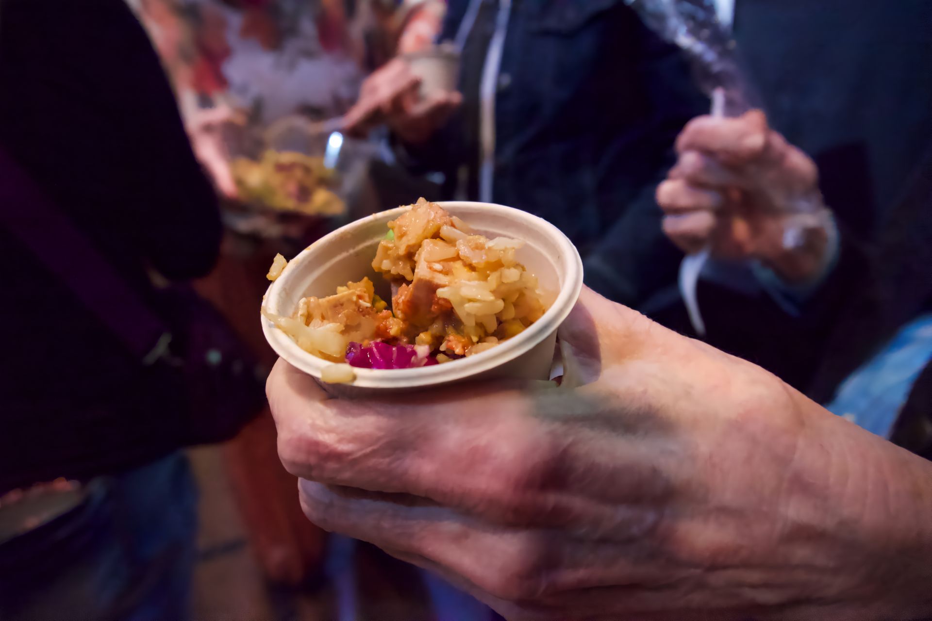 A person is holding a cup of food in their hand.