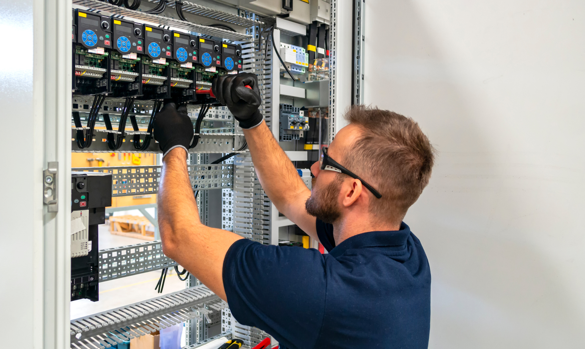 Man in safety glasses and gloves working on electrical panel. Man in safety glasses and gloves working on electrical panel.