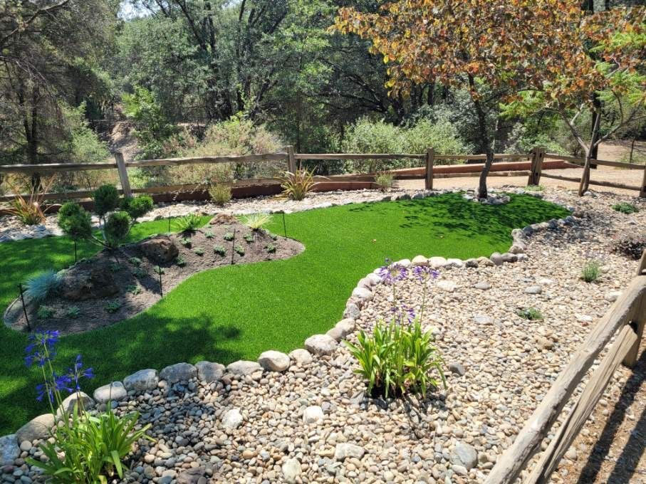 Landscaped yard with artificial turf, river rock, and drought-tolerant plants