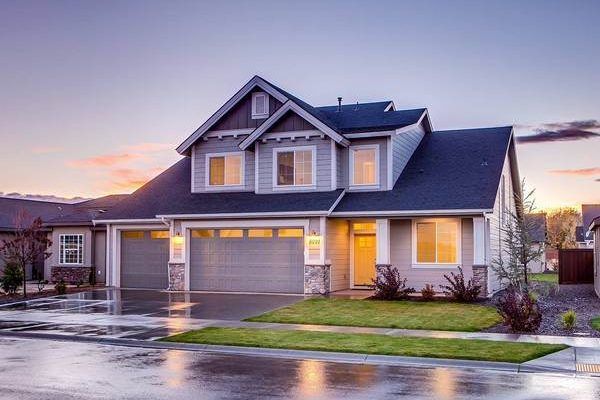 Two-story home with a dark shingle roof at dusk
