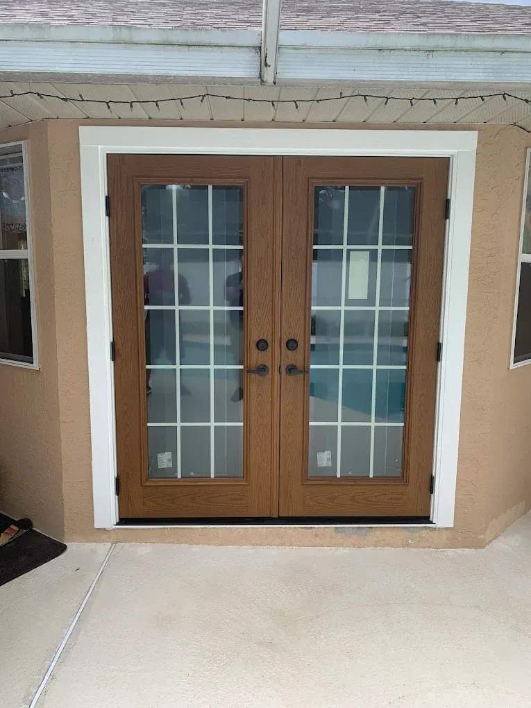 Wooden double front doors with glass panes and white trim at a home entrance