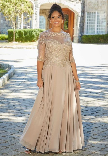 Woman in a gold beaded gown standing outdoors on a sunny walkway