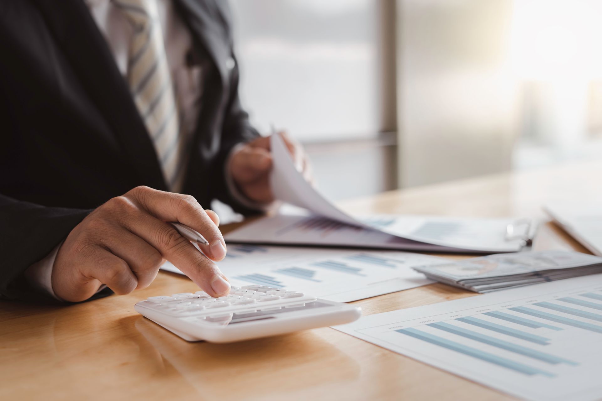 Person using a calculator and reviewing financial documents at a desk