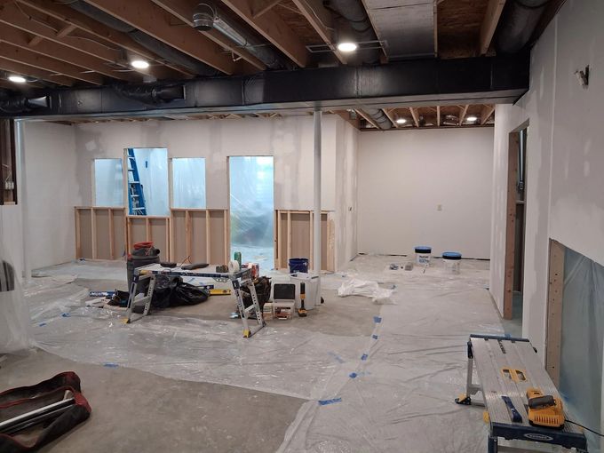 Empty room under renovation with unfinished walls, exposed ceiling beams, and construction materials on the floor