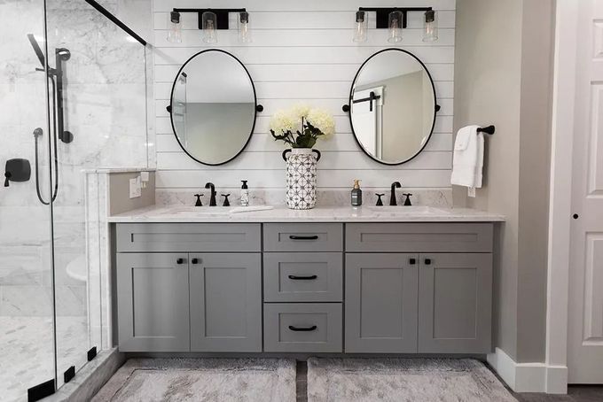 Modern gray double-sink bathroom vanity with round mirrors and marble tile walls