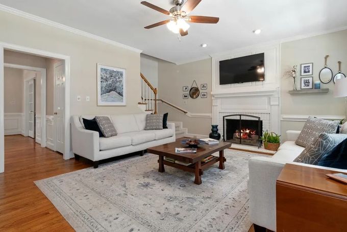 Bright living room with white sofa, fireplace, mounted TV, coffee table, and hardwood floors