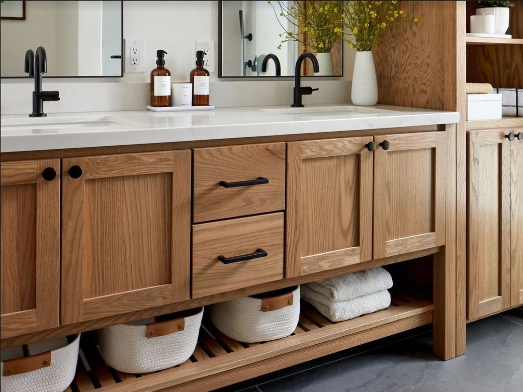 Wooden bathroom vanity with sink, black faucets, and woven baskets on the lower shelf