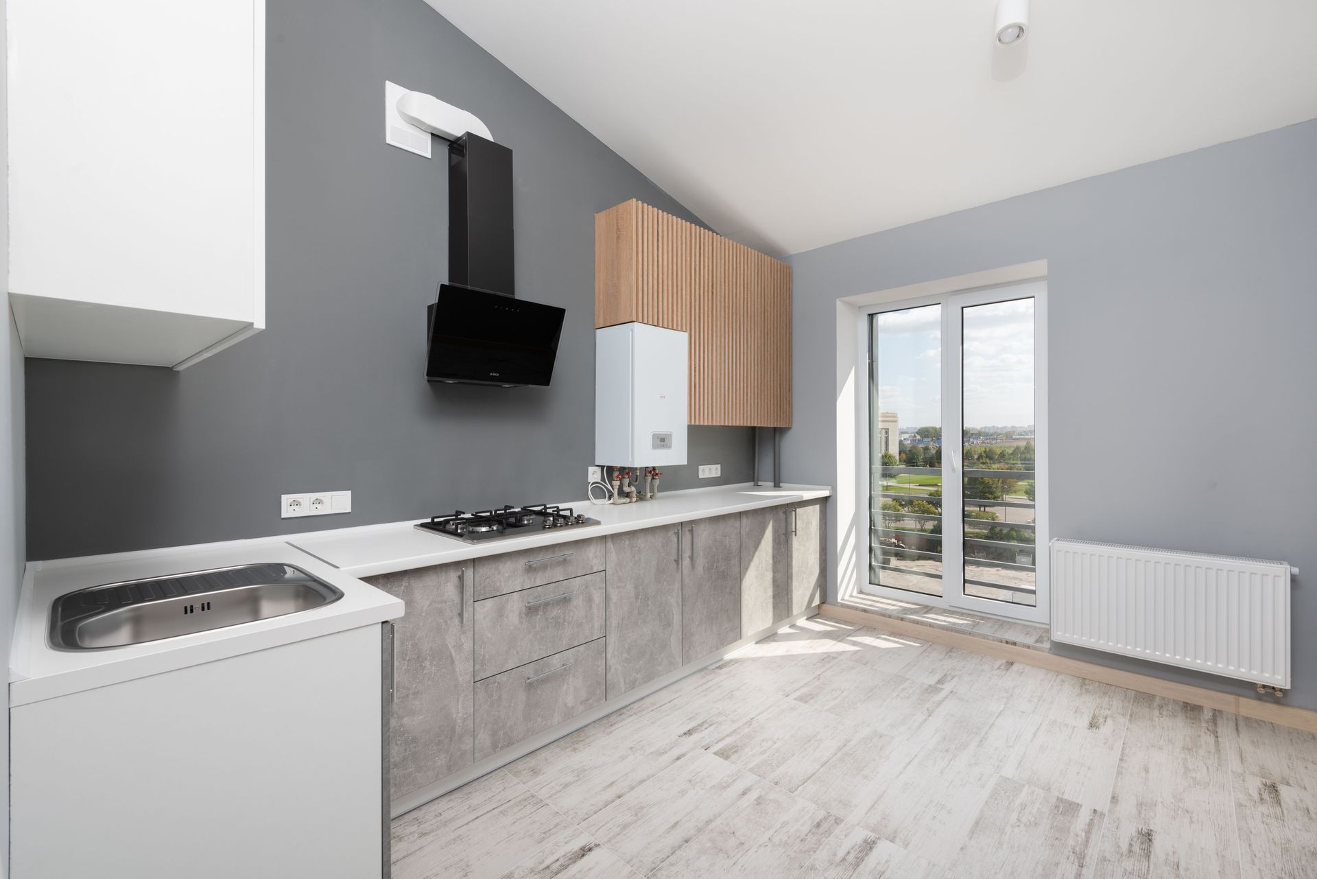 Modern kitchen with gray cabinets, wood accents, white appliances, and glass doors to a balcony