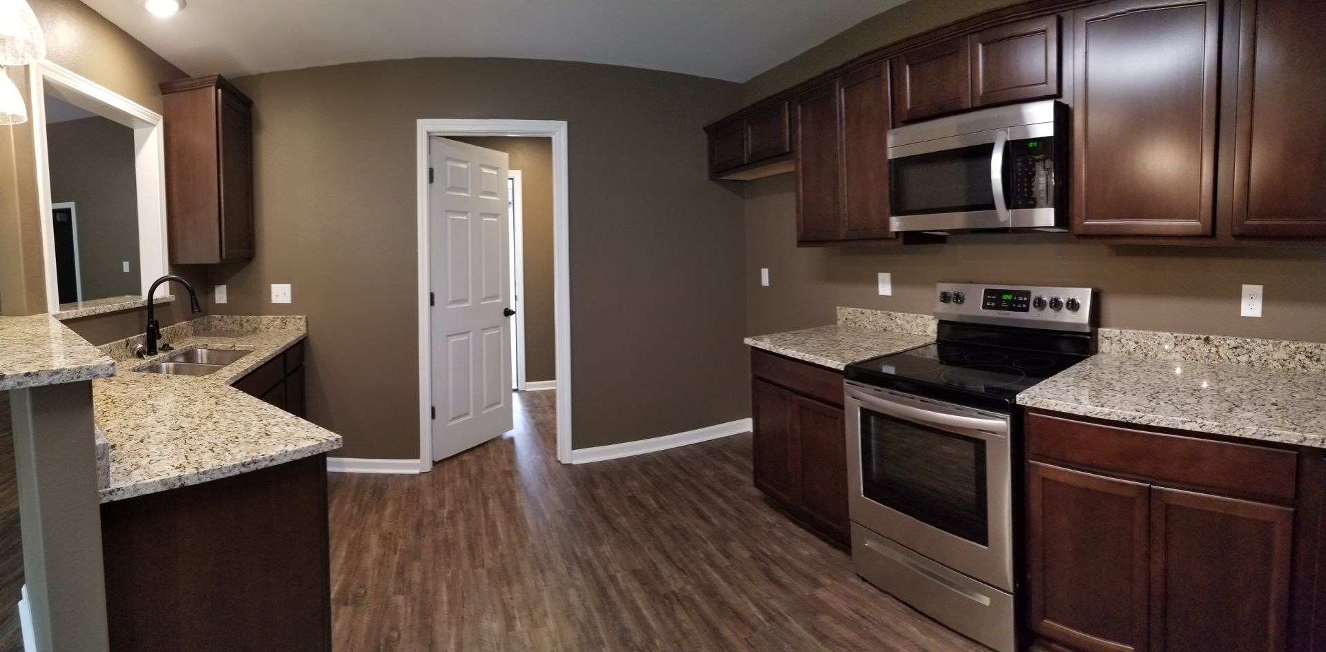 Kitchen with dark cabinets, granite countertops, and stainless steel appliances.