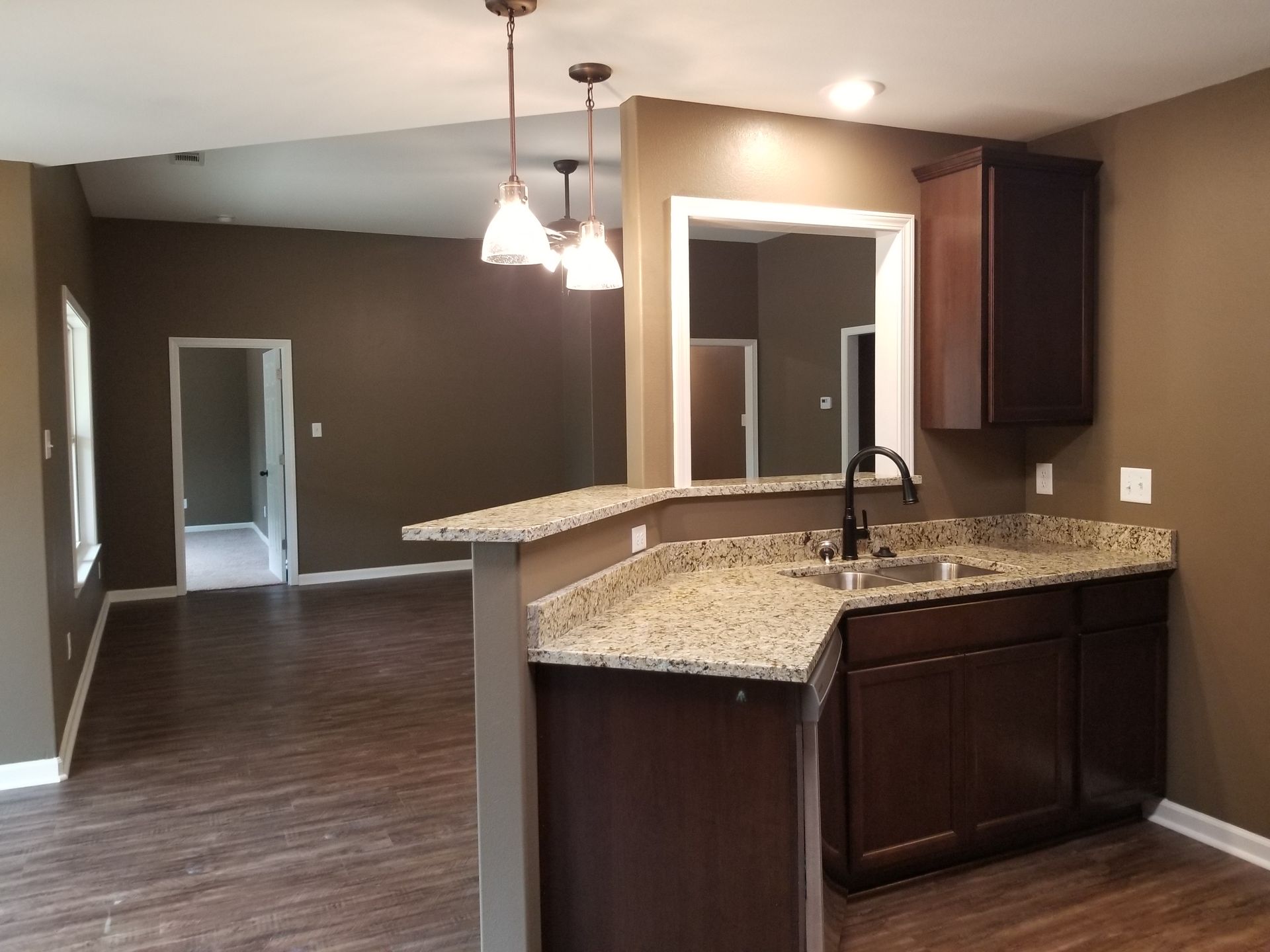Kitchen with dark cabinets, granite countertops, and open floor plan to living space.