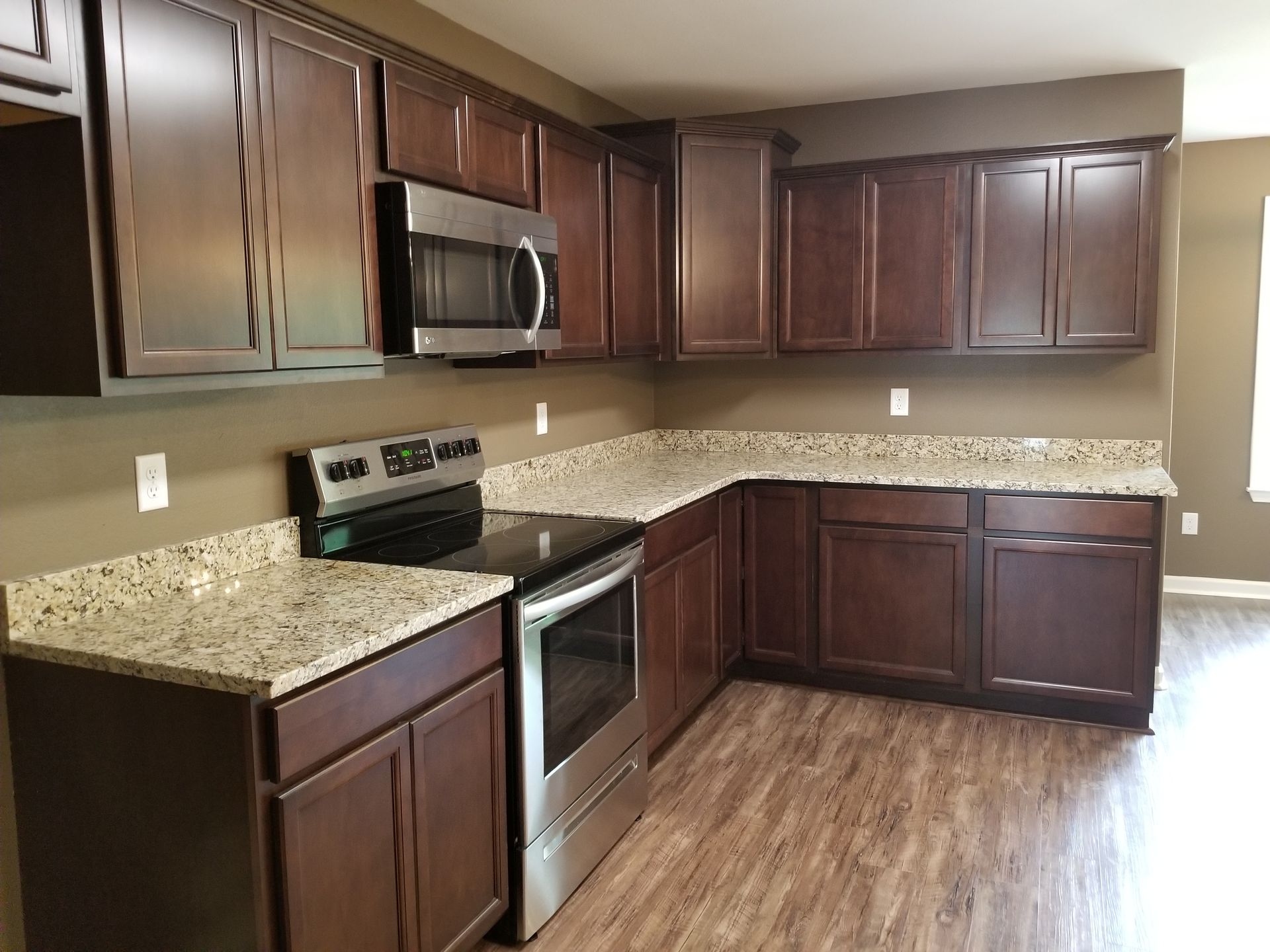 Dark wood kitchen cabinets, stainless steel appliances, granite countertops, and hardwood floors.