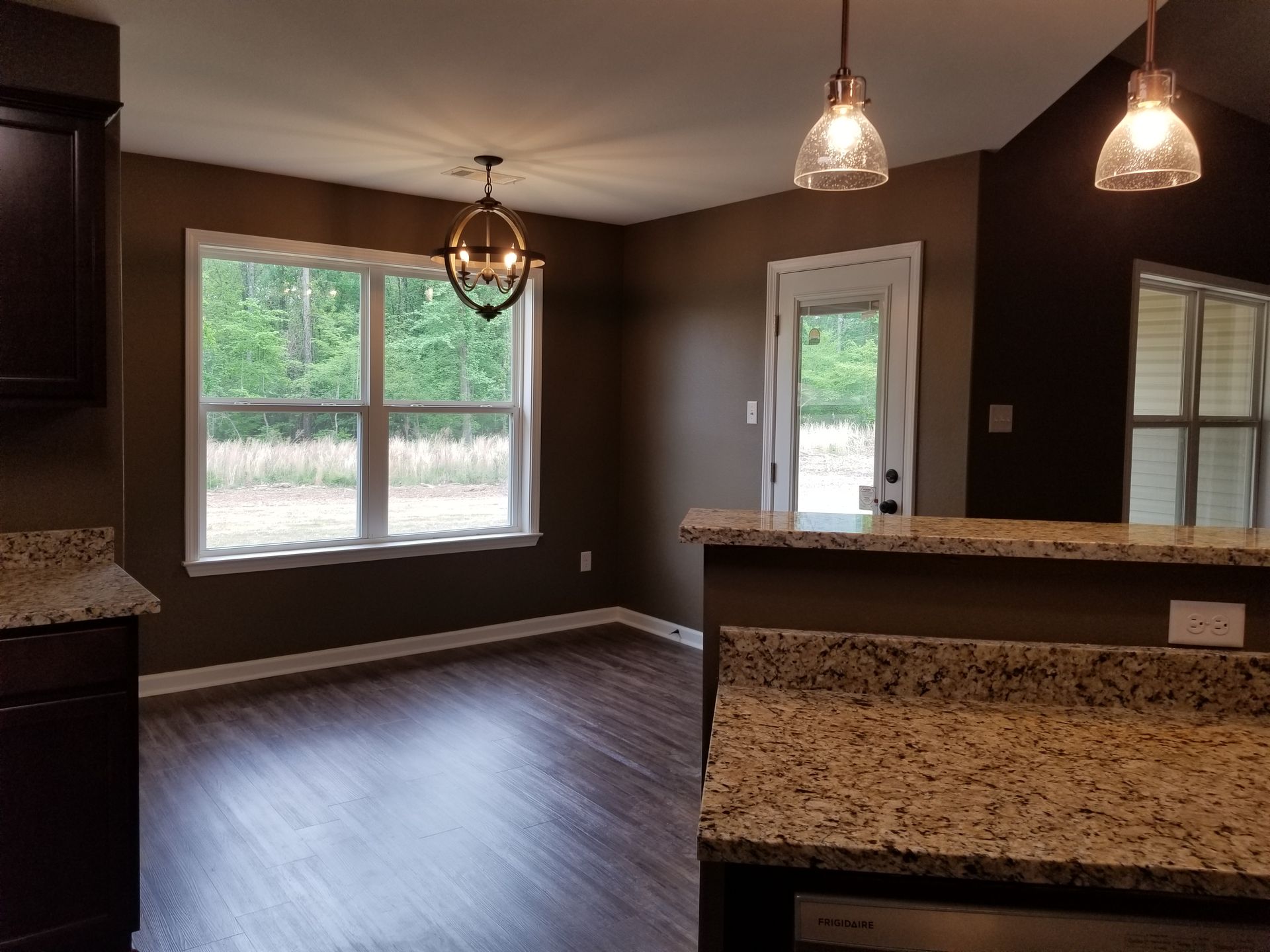 Dining area with dark brown walls, hardwood floors, and granite countertops.