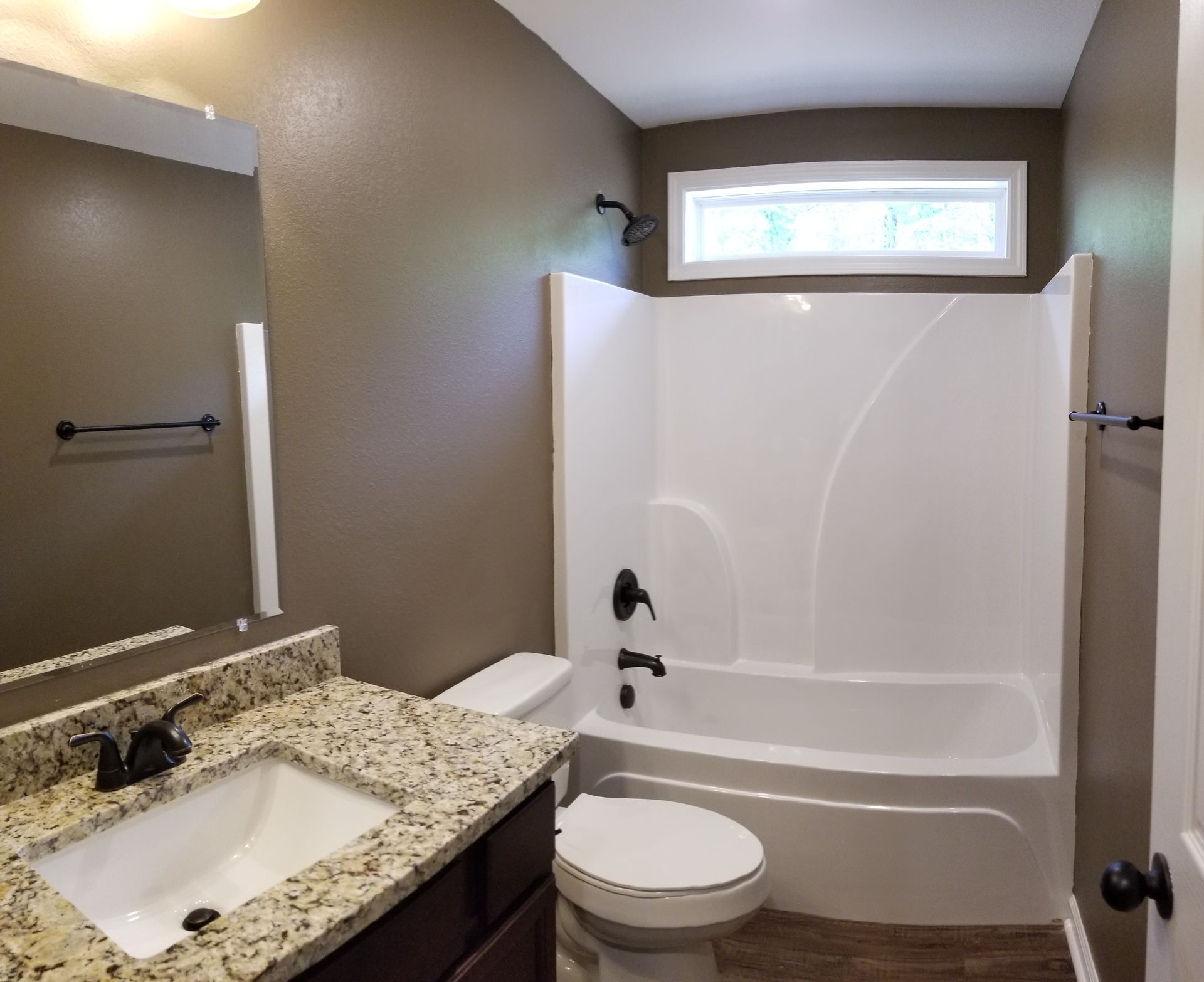 Bathroom with a tub/shower, toilet, vanity, and dark brown walls.