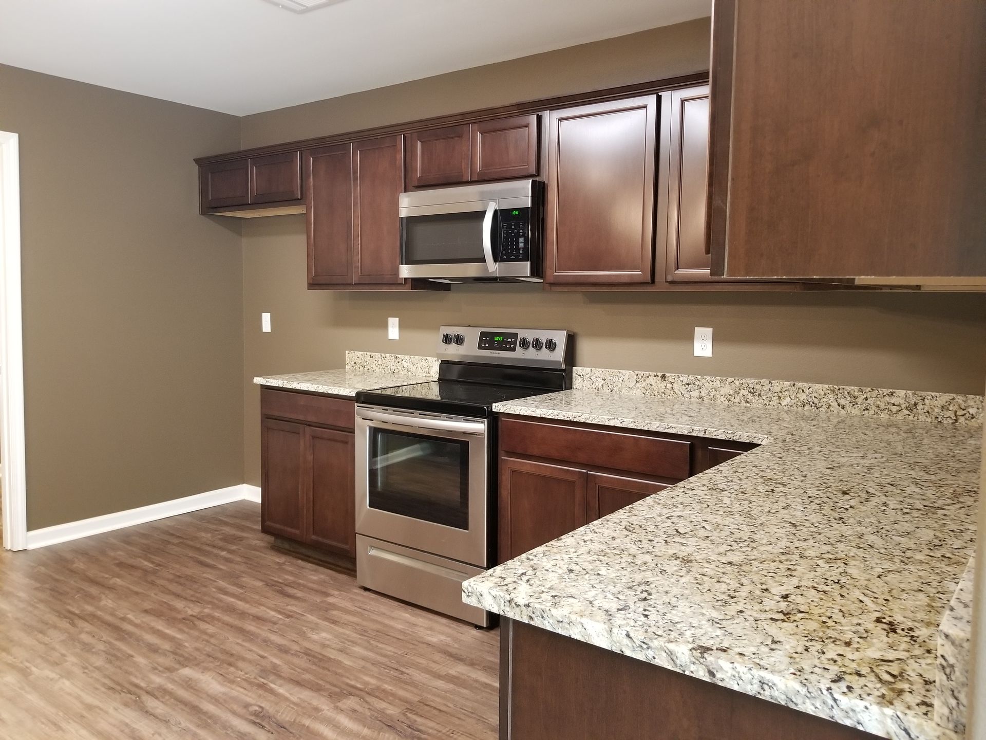 Kitchen with dark brown cabinets, stainless steel appliances, and granite countertops.