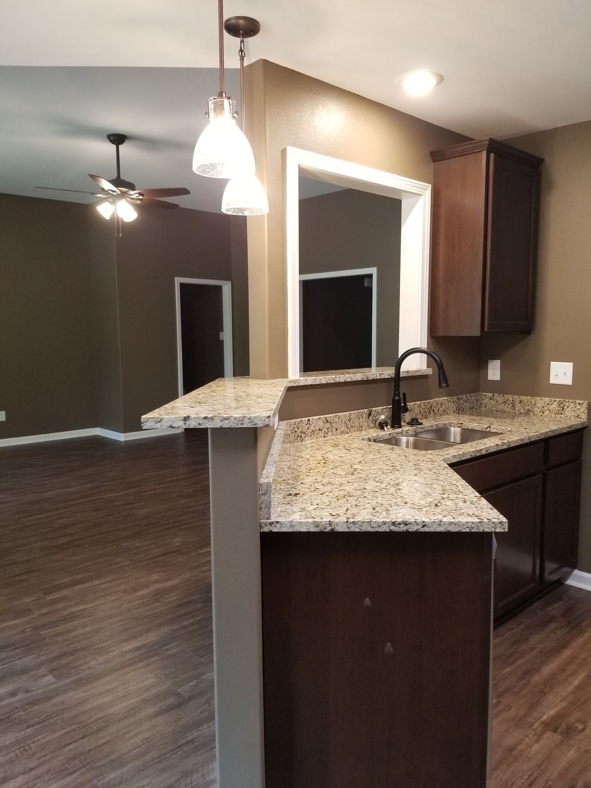 Kitchen with dark cabinets, granite countertops, and a pass-through to the living area.