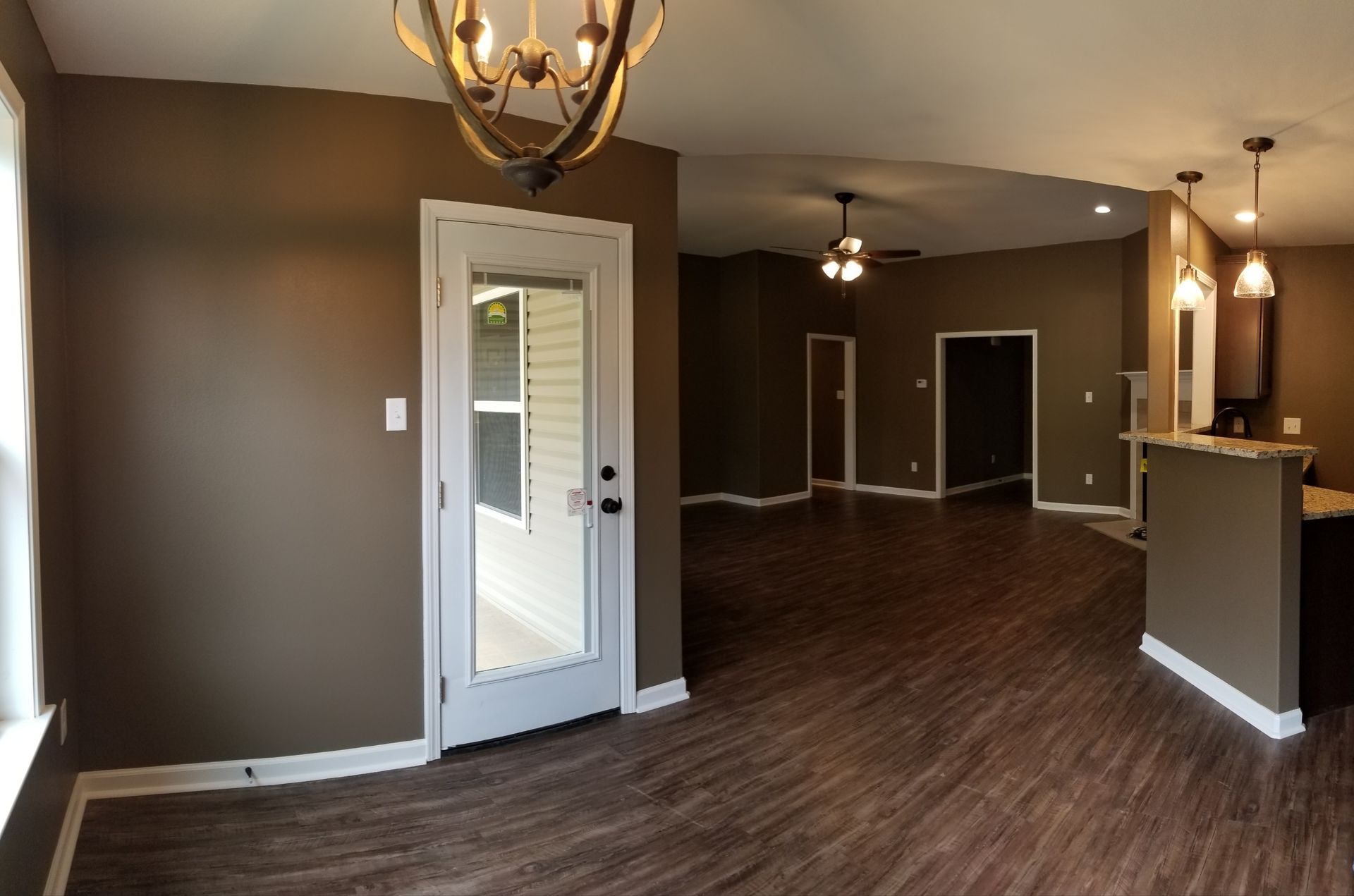 Interior view of a home with brown walls, wood floors, and a door to the outside.