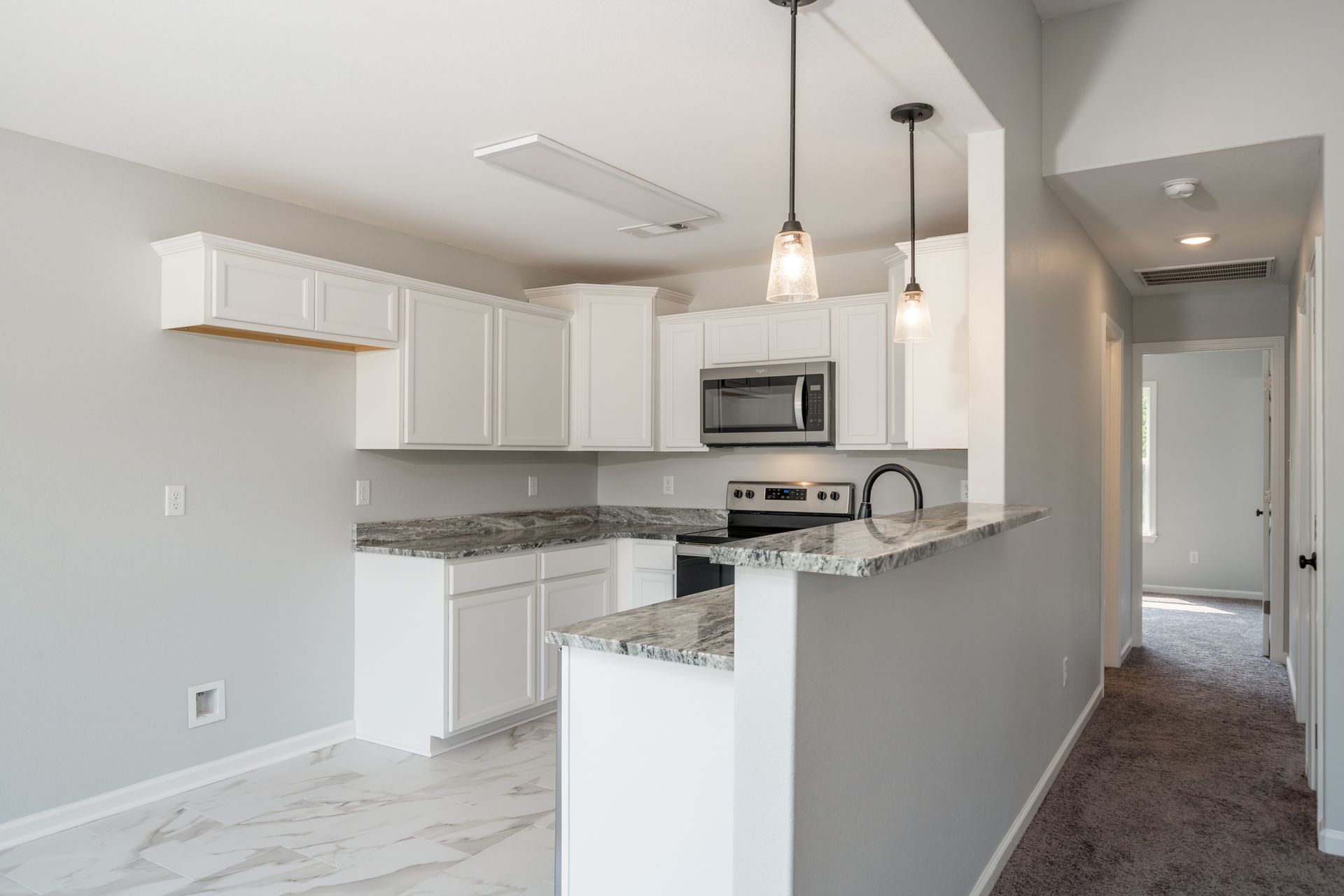 Bright kitchen with white cabinets, granite countertops, and stainless steel appliances.