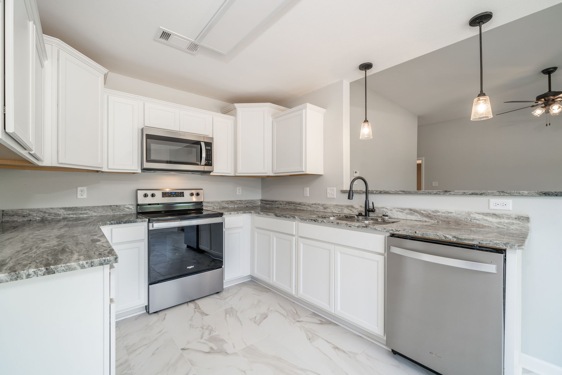 Bright white kitchen with stainless steel appliances and gray countertops.