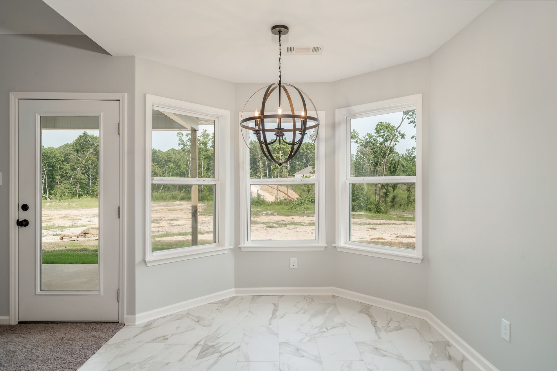 Bright dining nook with arched windows, light gray walls, marble floor, and a modern chandelier.