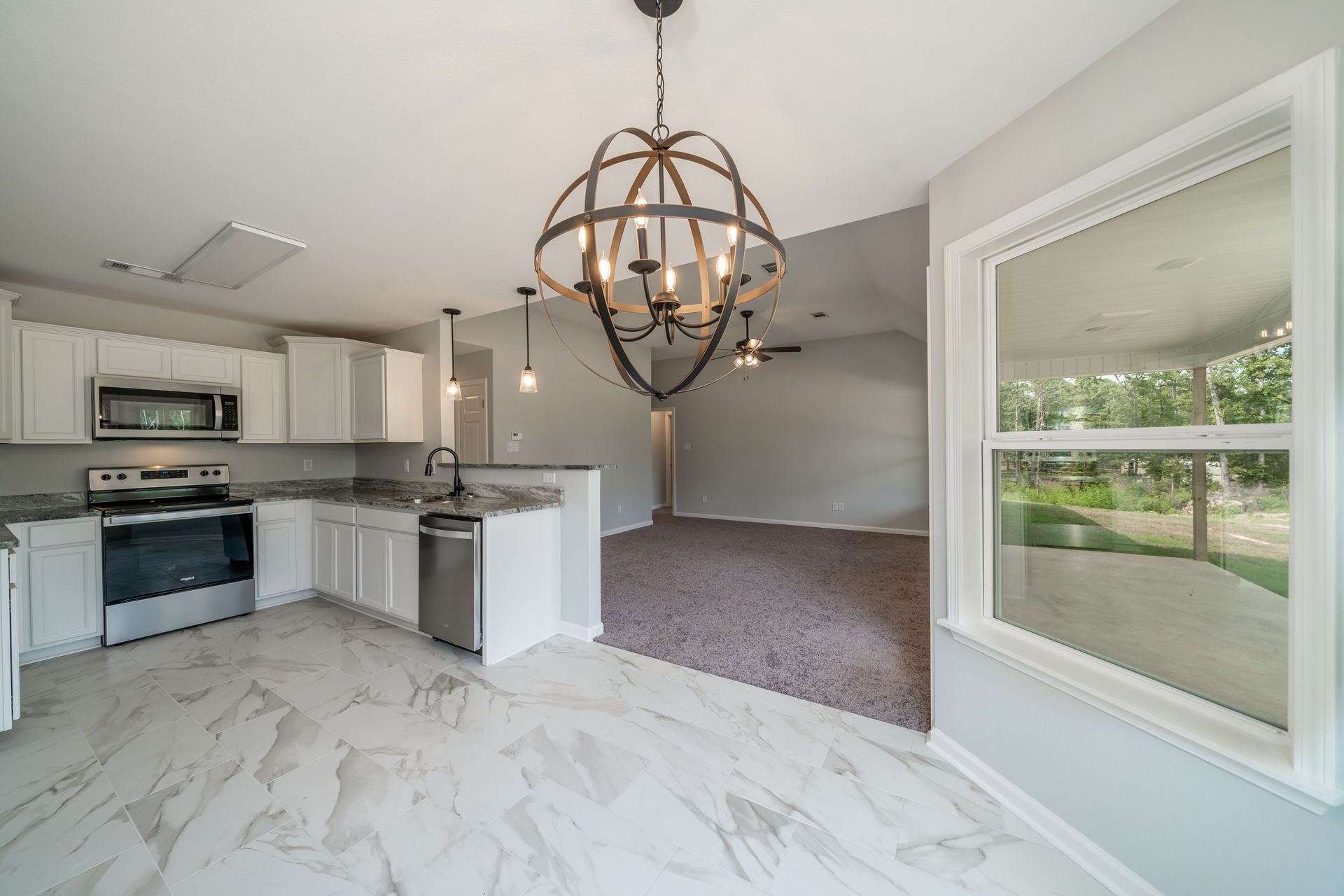 Spacious kitchen with white cabinets, stainless steel appliances, and a large, ornate chandelier.