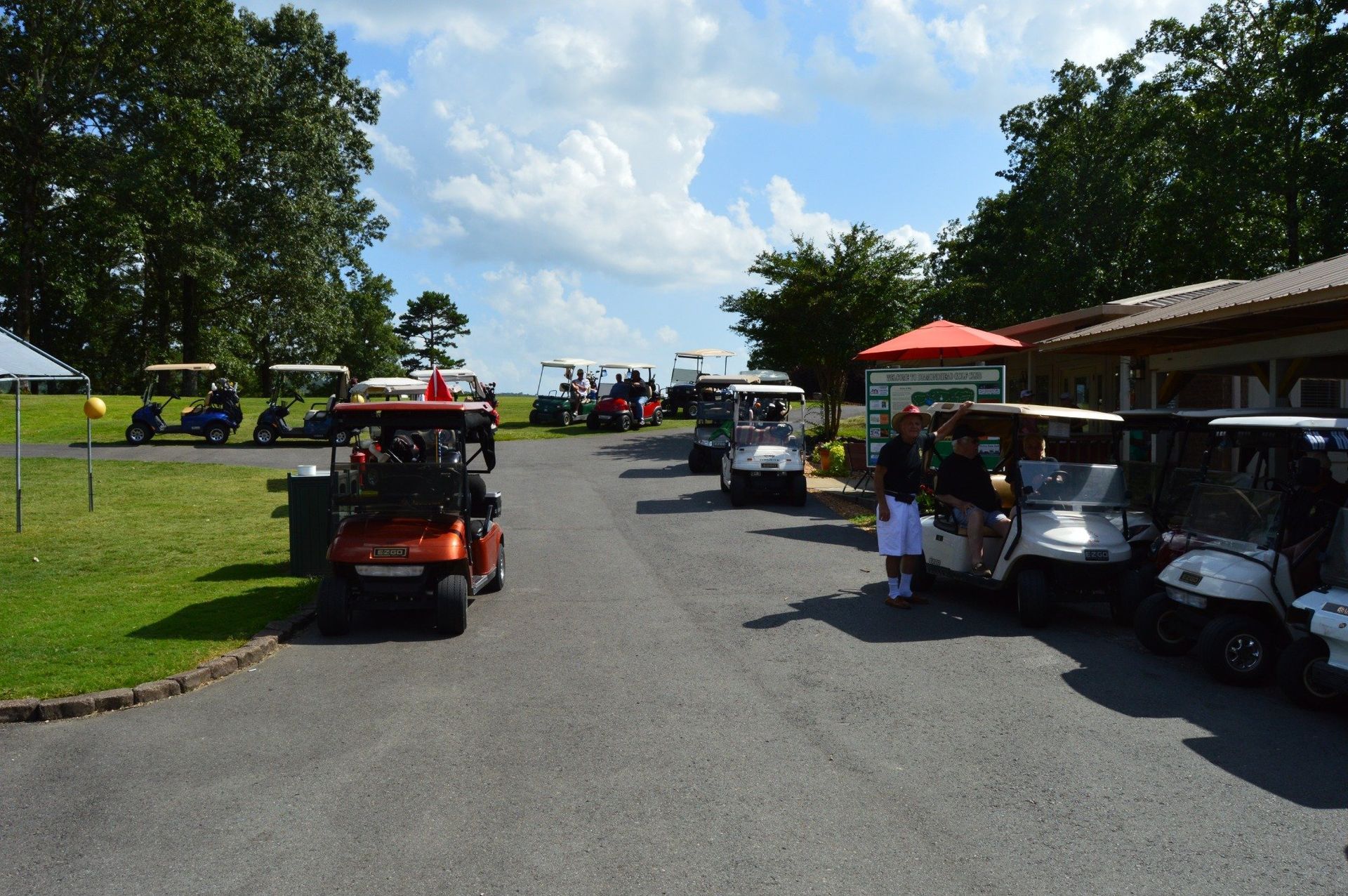 Golf carts parked near a building, under a cloudy sky.