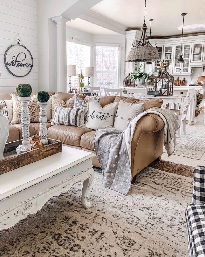 Cozy living room with leather sofa, white accents, decorative pillows, and a patterned rug.