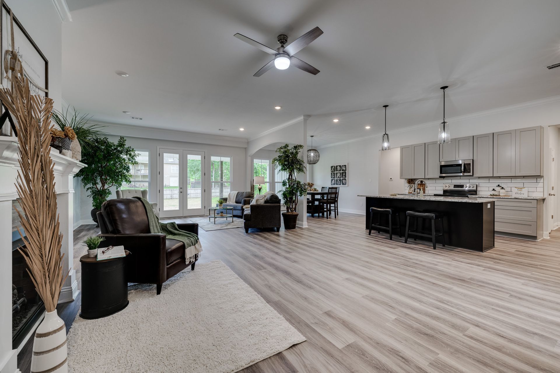 Open-concept living space: Living room with brown leather chairs, kitchen with a dark island, and white walls.