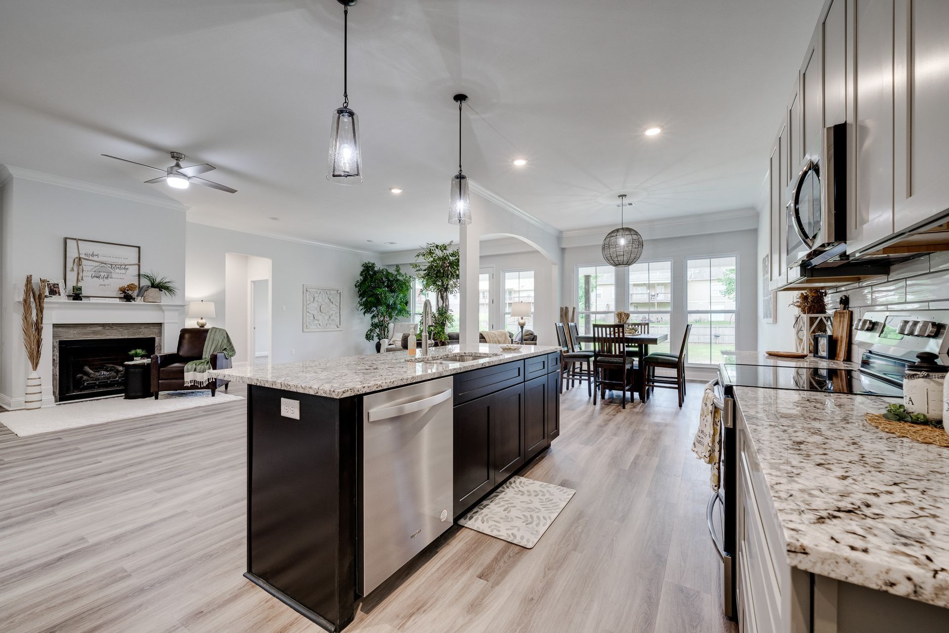Open-concept kitchen with island, stainless steel appliances, and dining area, with a view of the living room.
