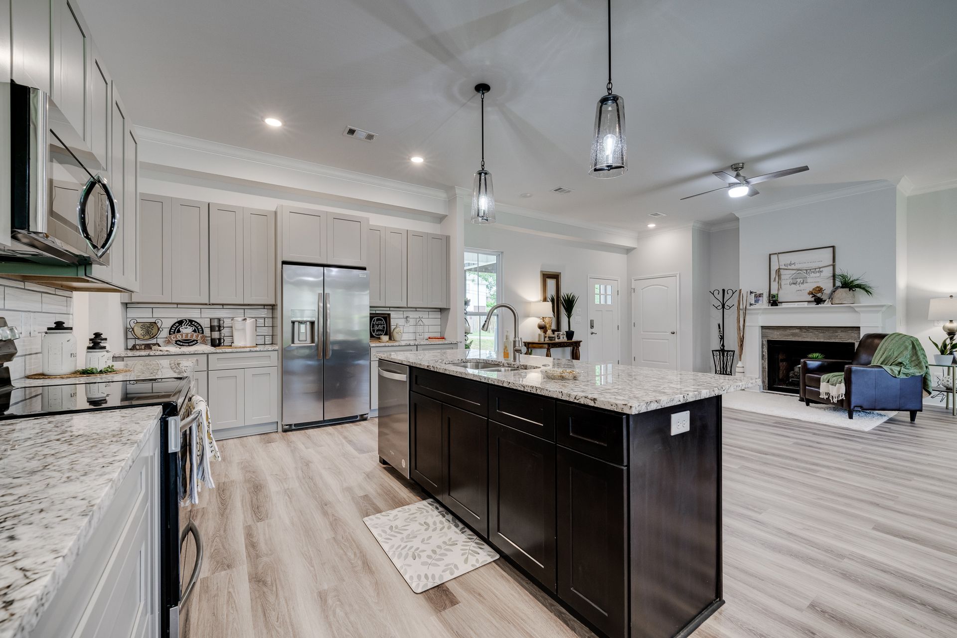 Modern kitchen with light wood floors, stainless steel appliances, and dark island.