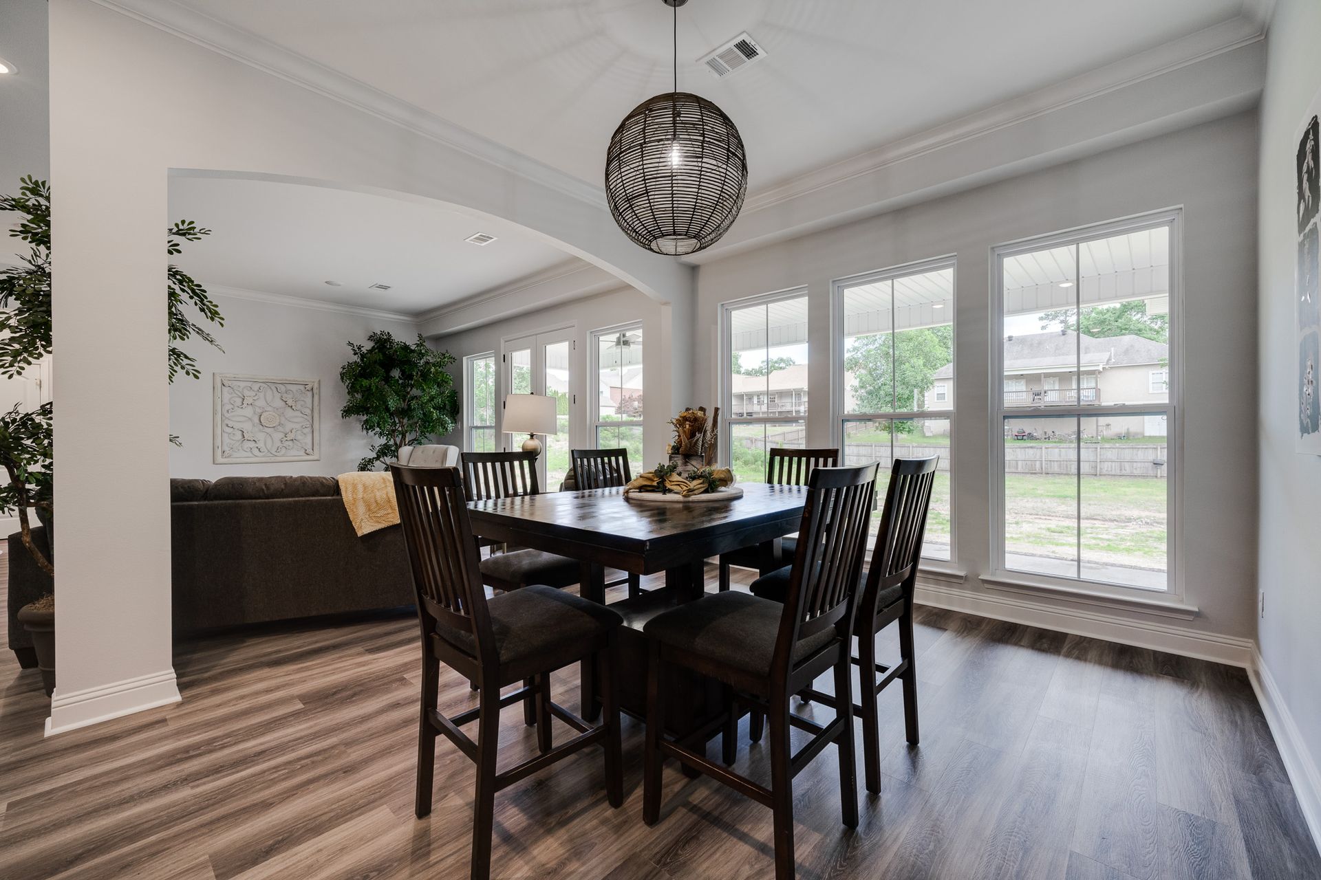 Dining room with dark wood table and chairs, hardwood floor, and large windows.