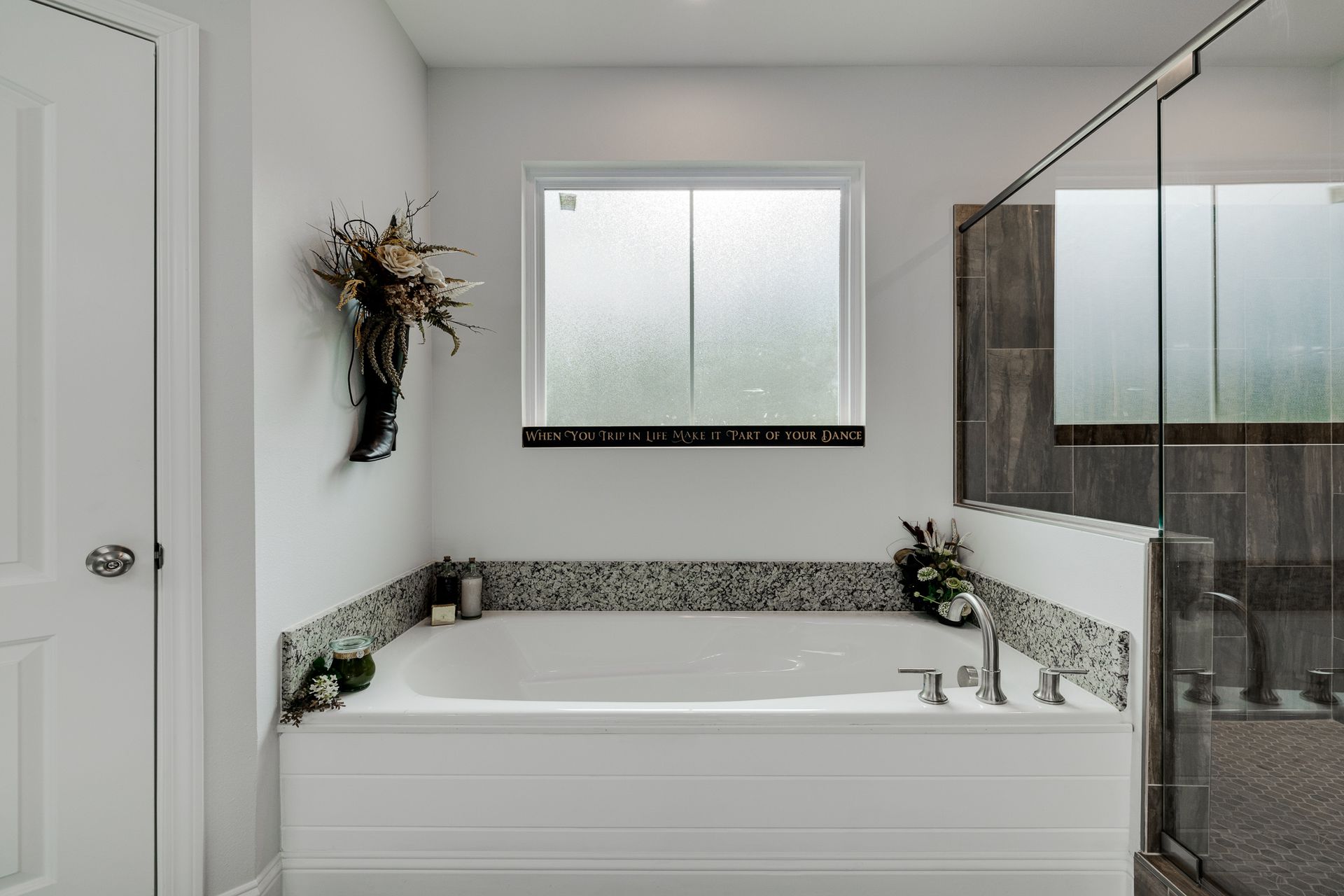 Bathroom with white bathtub, frosted window, and glass shower.