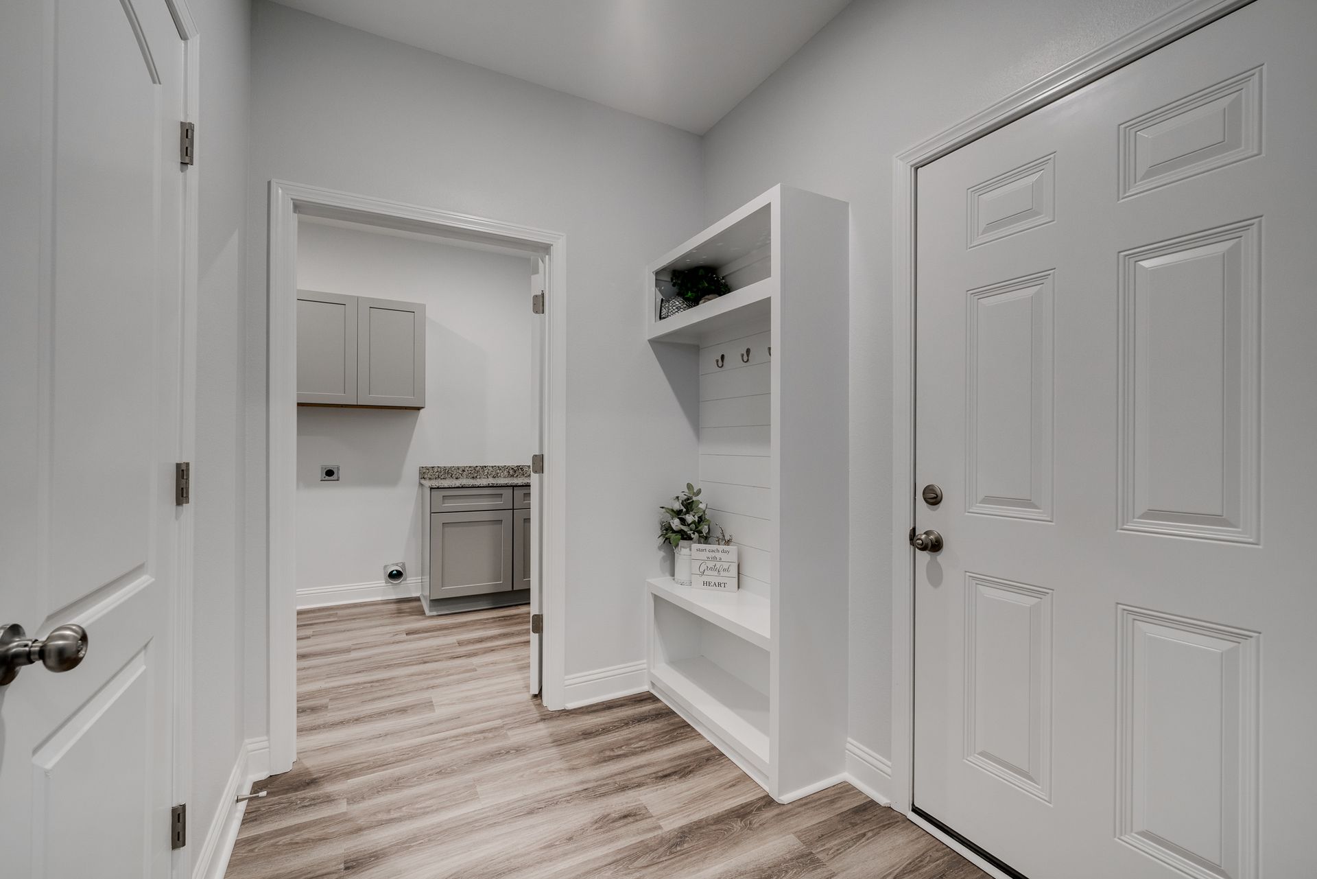 A light-filled entryway with a built-in storage unit, and a laundry room visible.