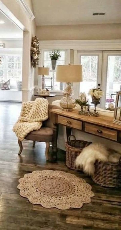 Cozy living space with rustic wood console table, woven baskets, a textured rug, and a plush throw over a chair.