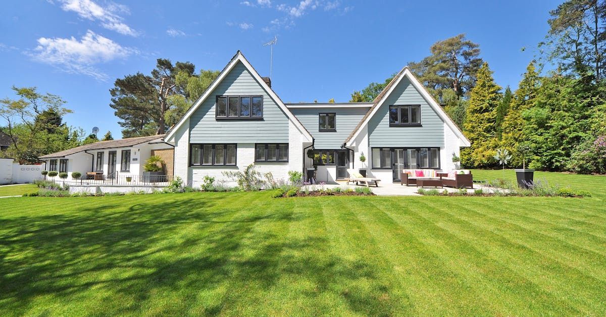 House with a large green lawn, two gabled sections, light blue and white exterior.