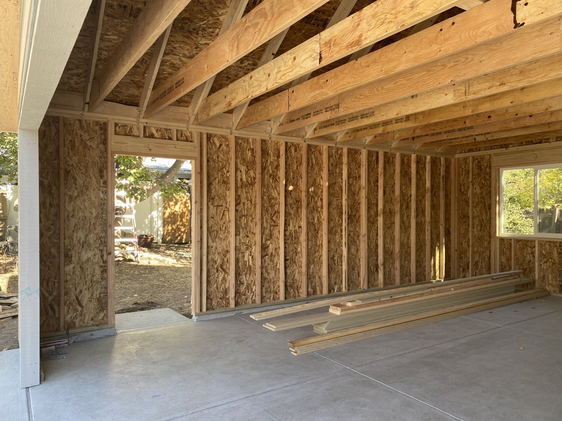 Interior of a garage under construction, showing wooden framework, concrete floor, and door/window openings.