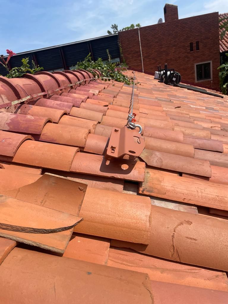 Red tiled roof with a metal anchor system for fall protection.
