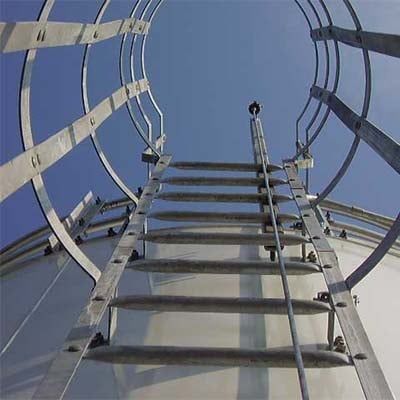 Metal ladder ascending a cylindrical structure against a blue sky.