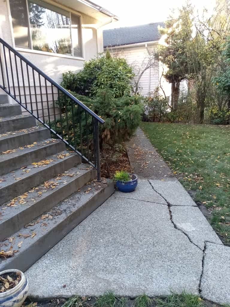 a cement sidewalk with a planter on the side of it