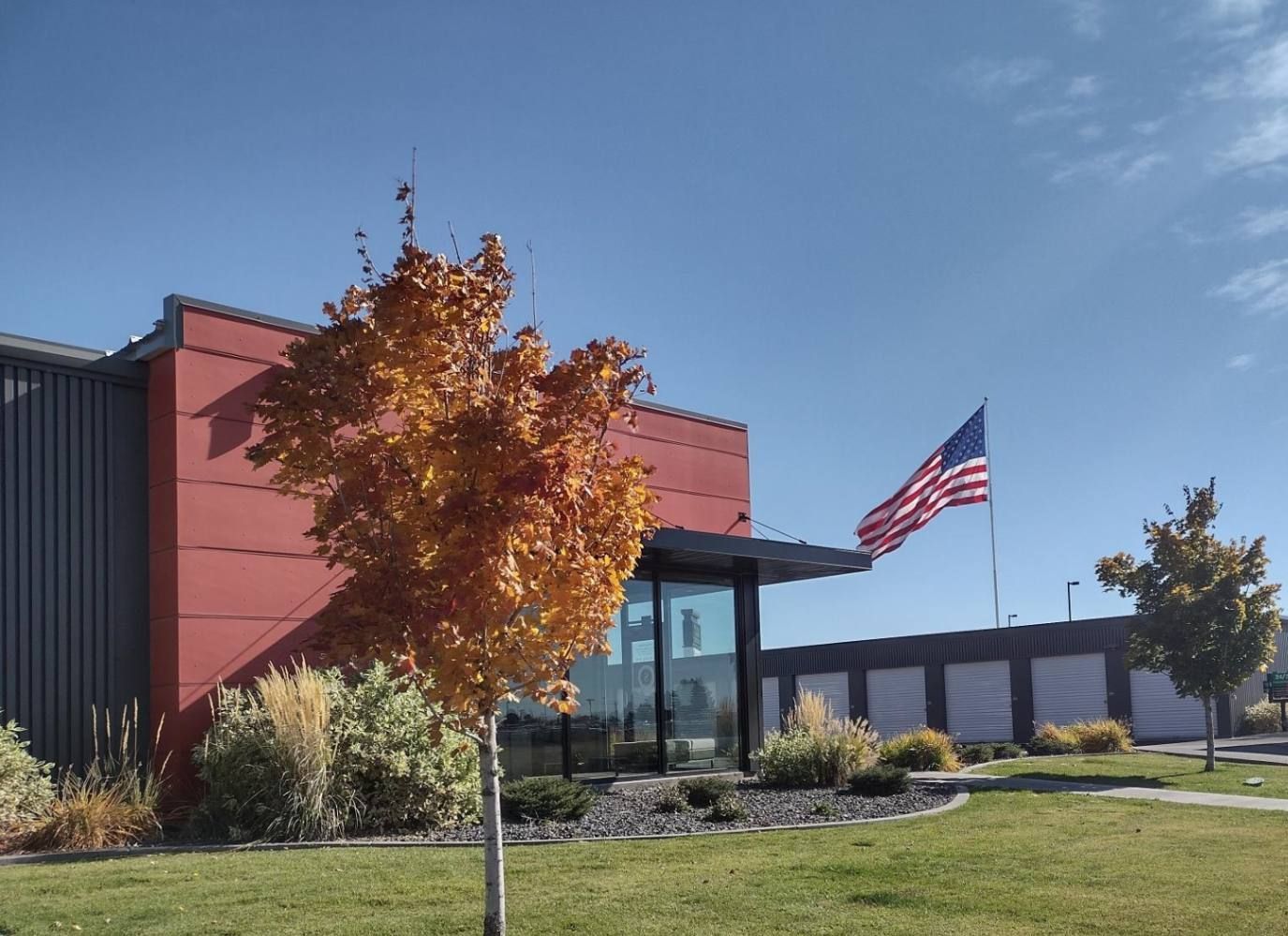 Building with red facade, American flag, fall foliage, and blue sky.
