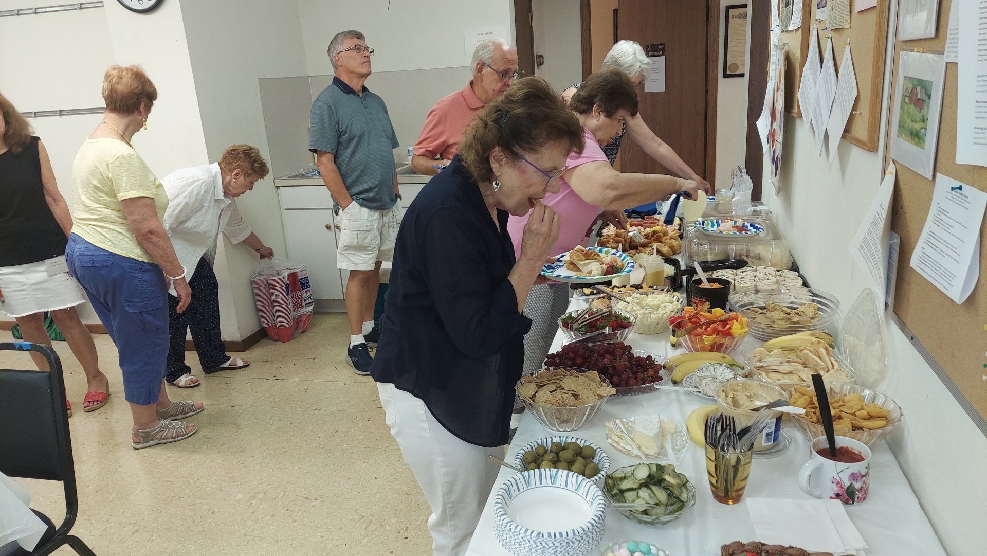 A group of people are standing around a table filled with food.