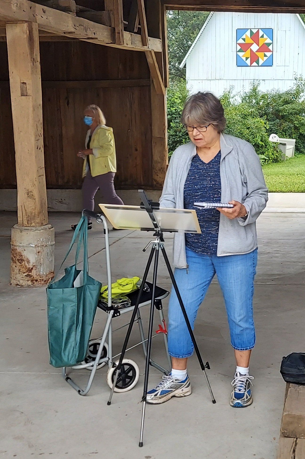 A woman is standing in front of a painting easel.