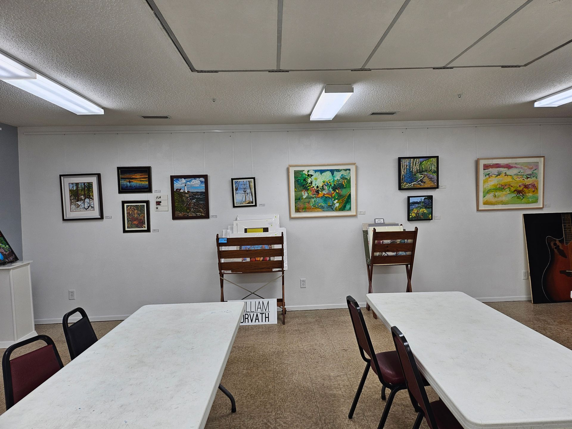 A room with tables and chairs and paintings on the wall.