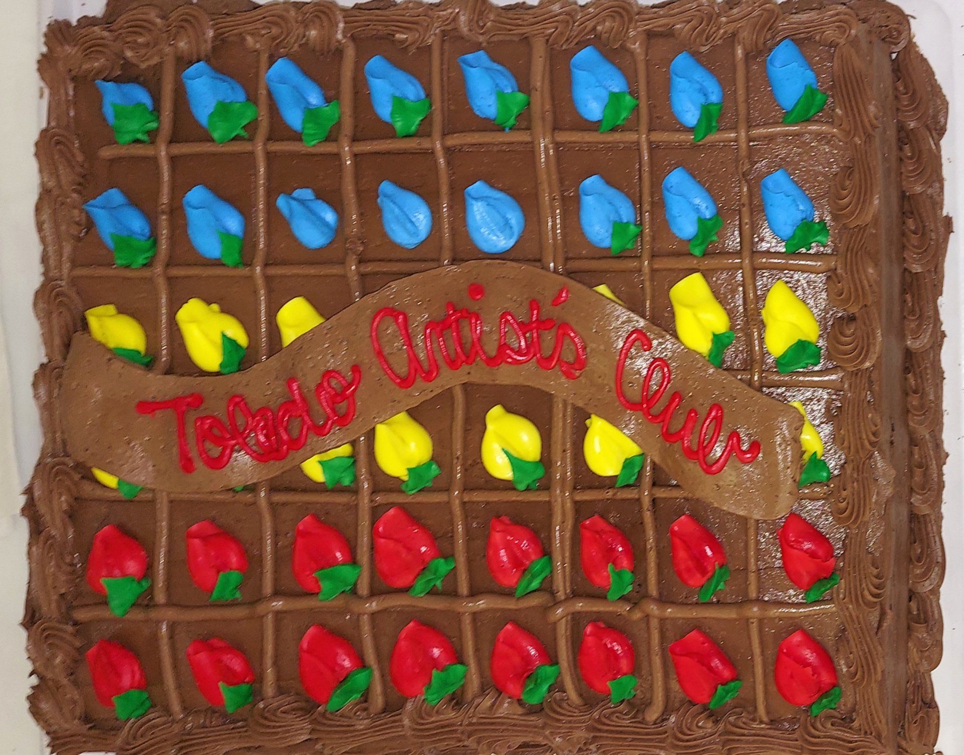 A chocolate cake that says toledo artists club on it