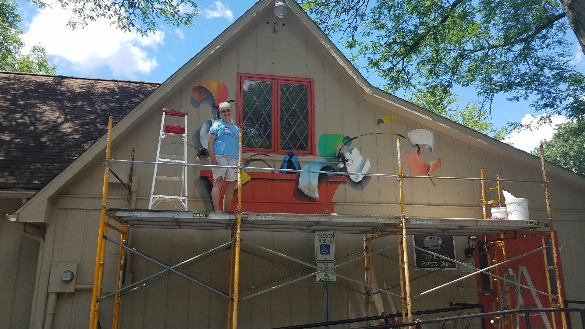 A woman is standing on a scaffolding on the side of a building.