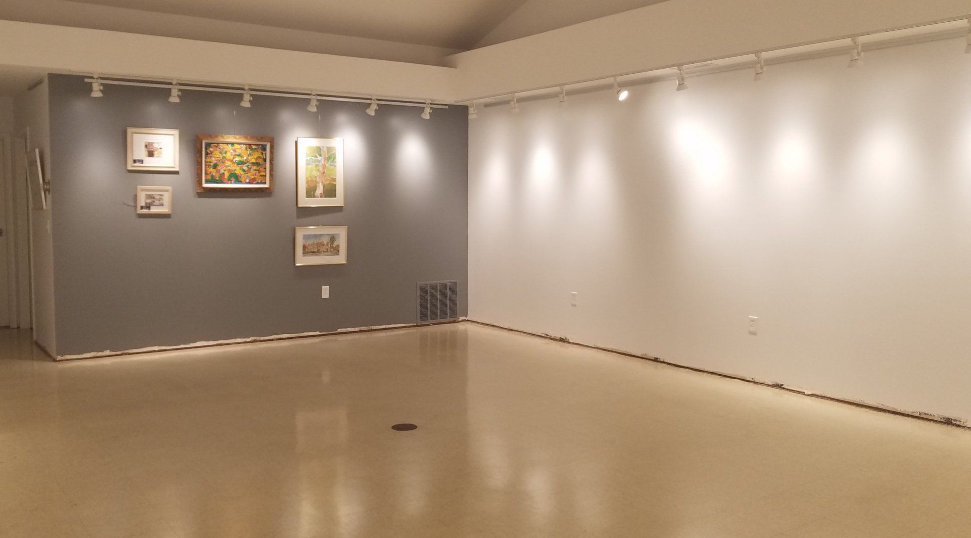 A large empty room with a lot of paintings on the wall.