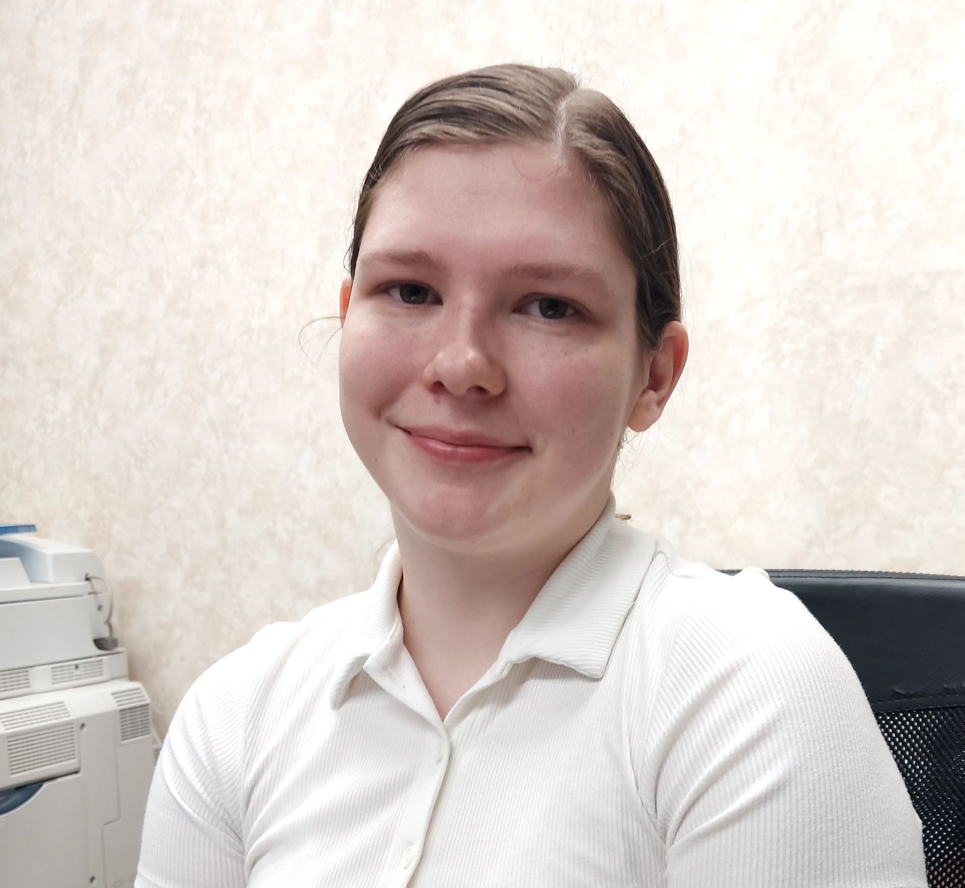 A woman in a white shirt sits in front of a printer