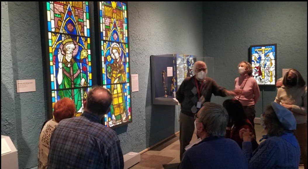 A group of people are looking at a stained glass window in a museum.
