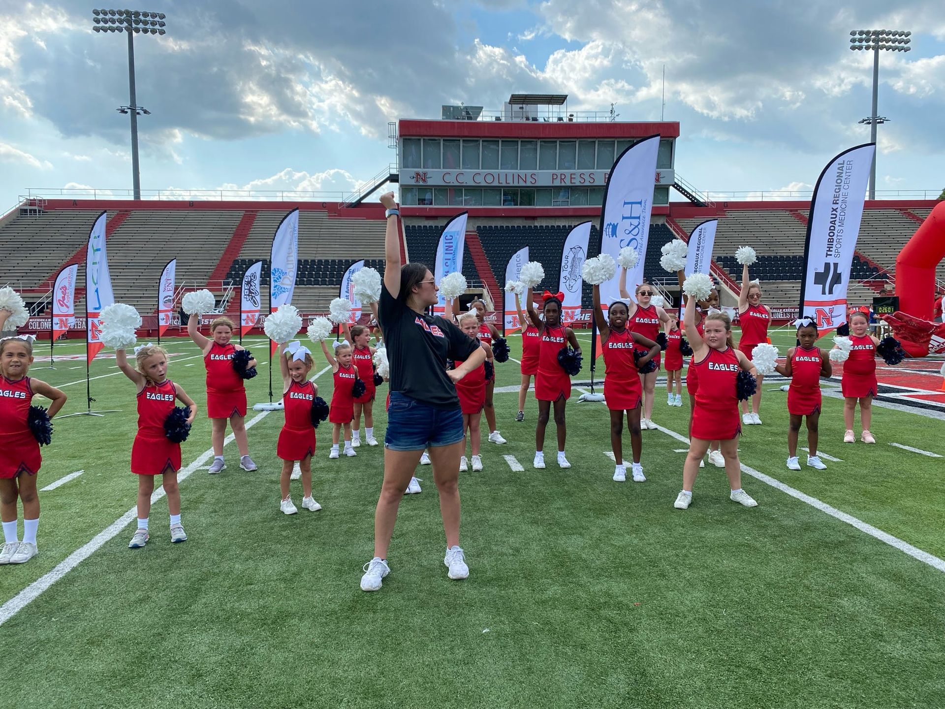 A group of cheerleaders are standing on a field holding pom poms.