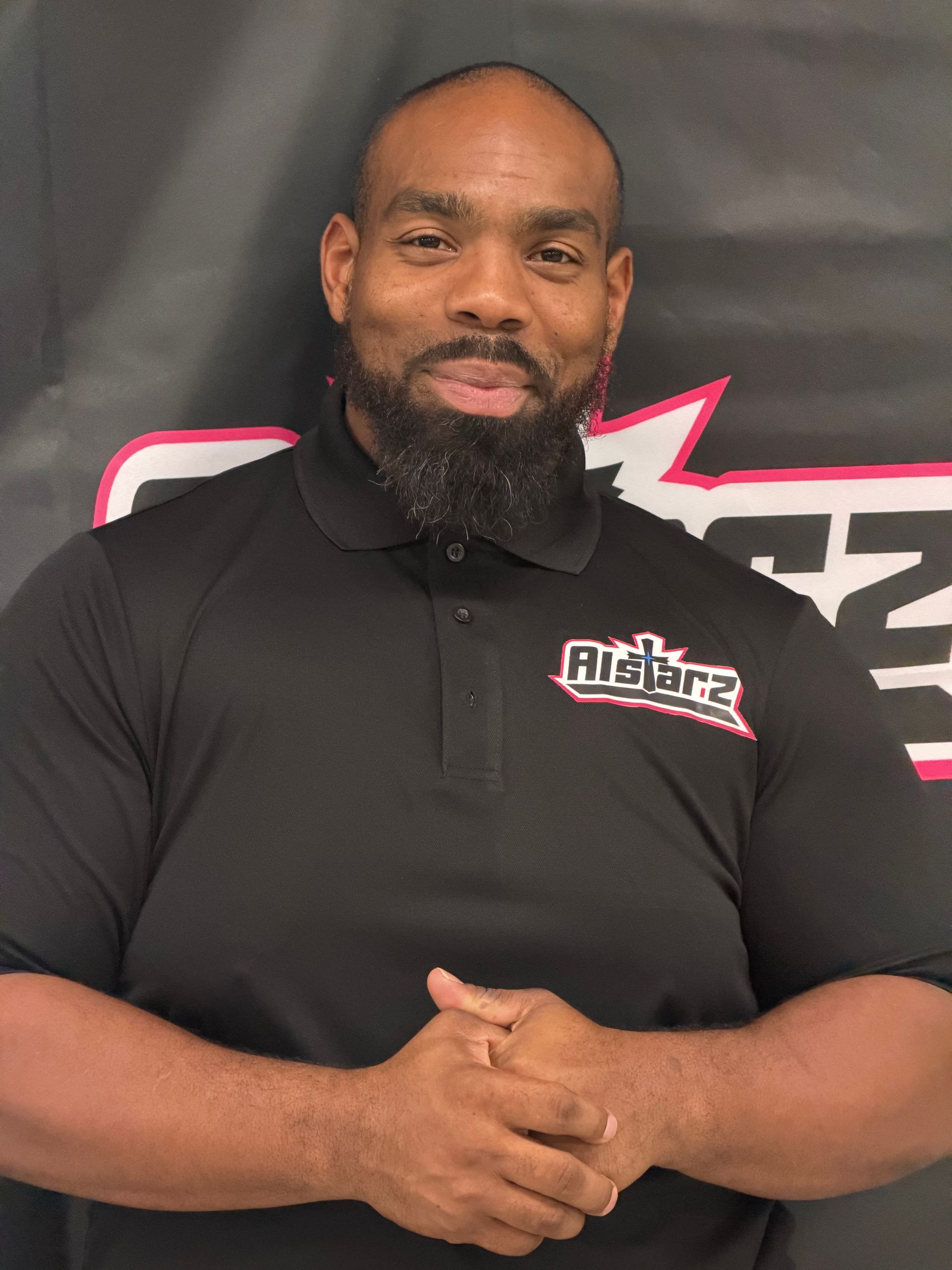A man with a beard is wearing a gray adidas polo shirt.