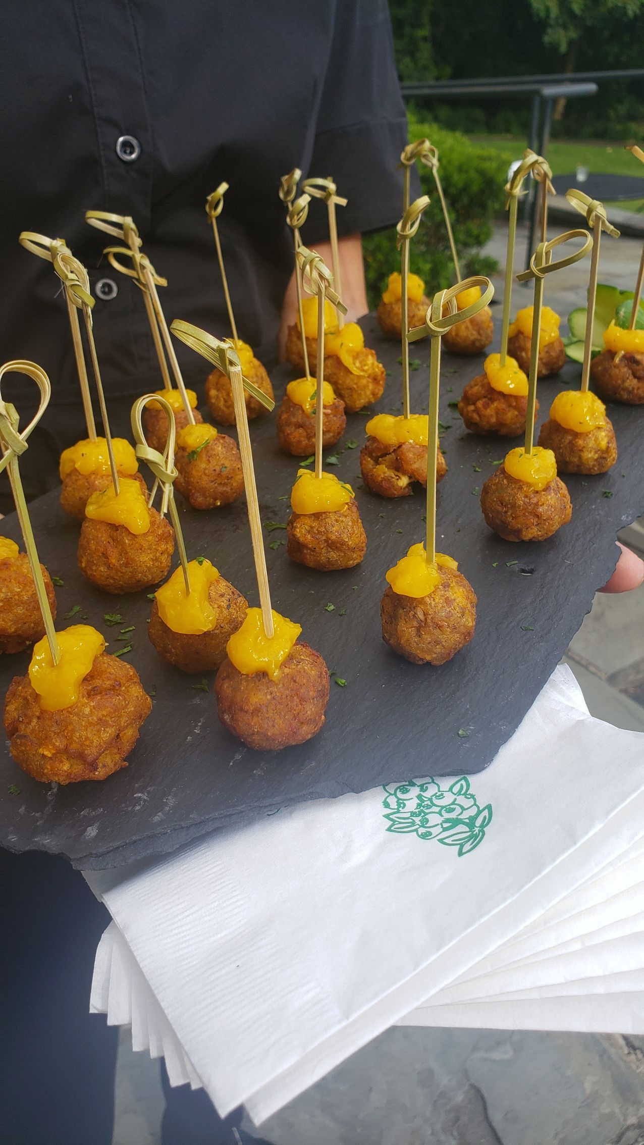 A person is holding a tray of food on sticks.